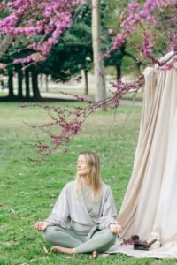 Serene moment of a woman meditating in a garden under flowering branches.